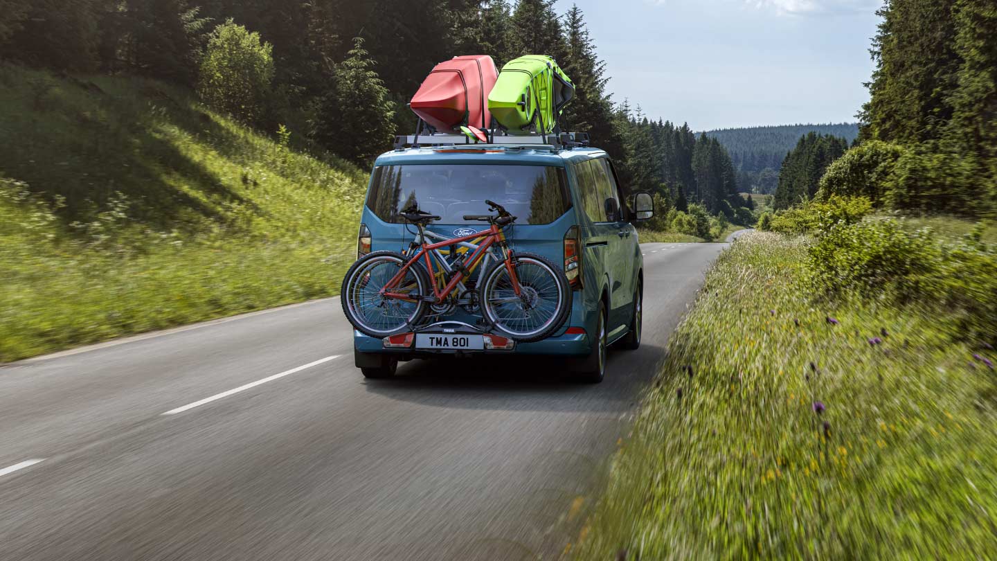 Blue Tourneo Custom with boats on roof and bike rack on the rear