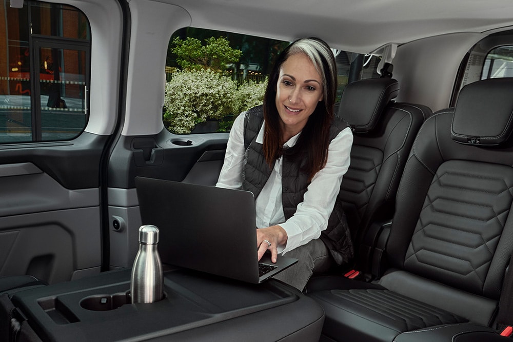Inside a Ford Tourneo Custom, a person works on a laptop.