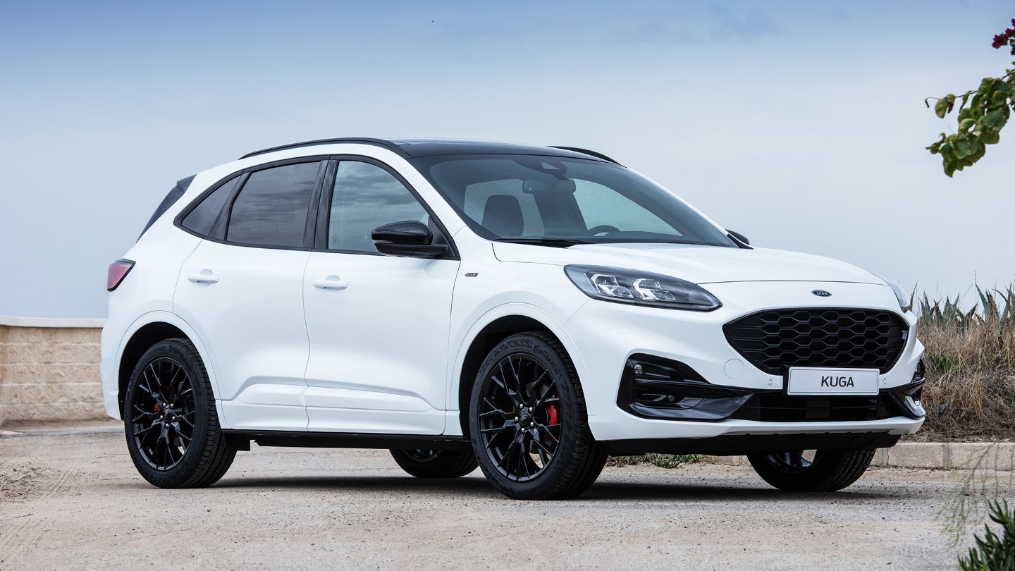 Ford Kuga Black Package in Weiß. 3/4 Seitenansicht vor einer Mauer und einem Feld parkend