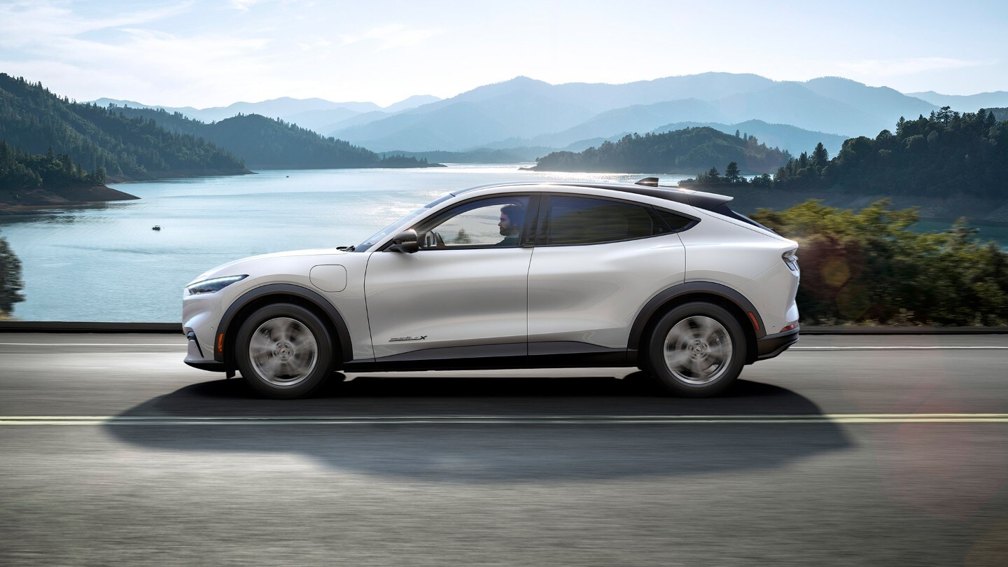 Silver All Electric Ford Mustang Mach-E driving sunny cliffs and sea