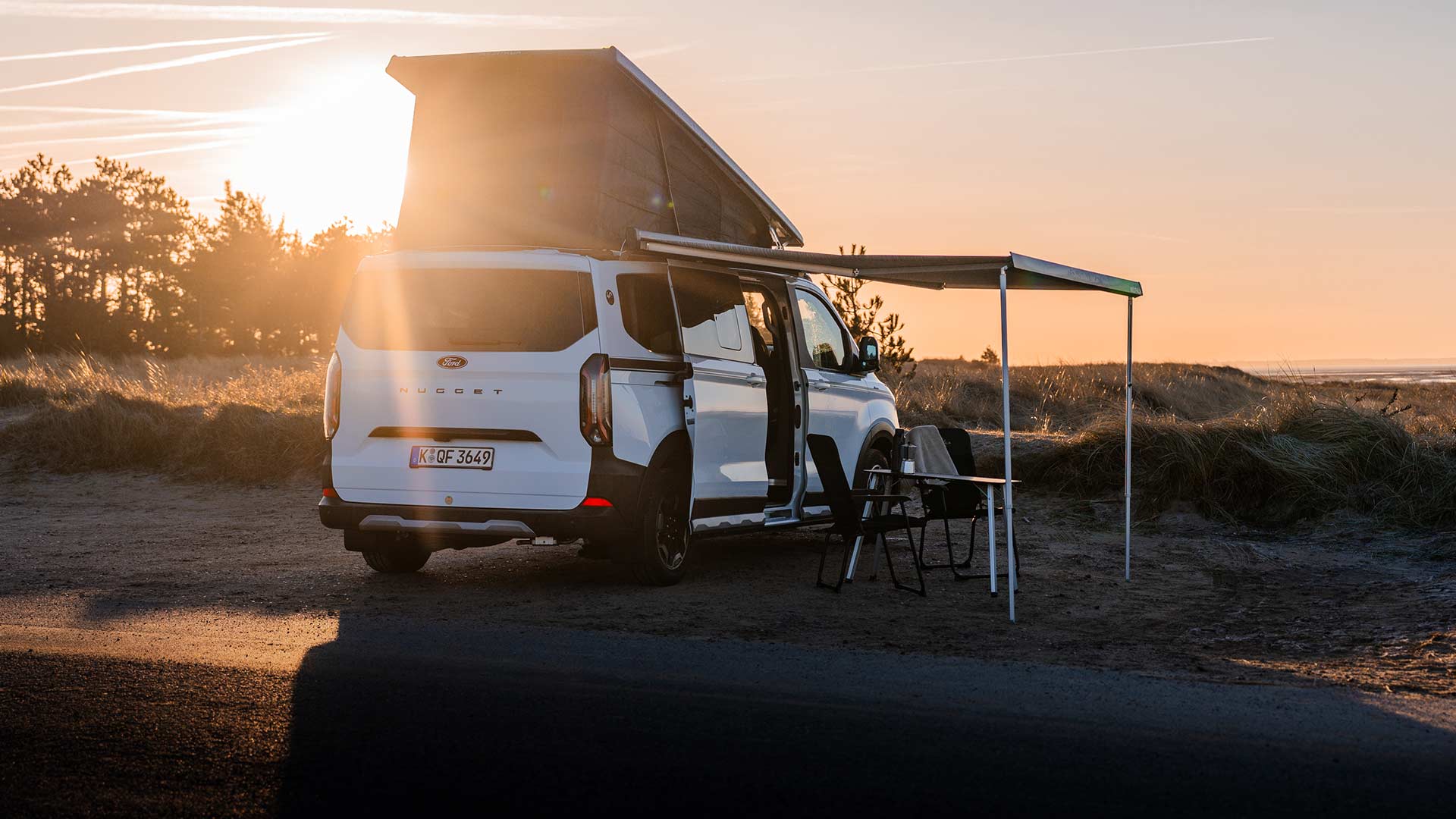 Person legt ein Paket in einen roten Ford Transit Custom