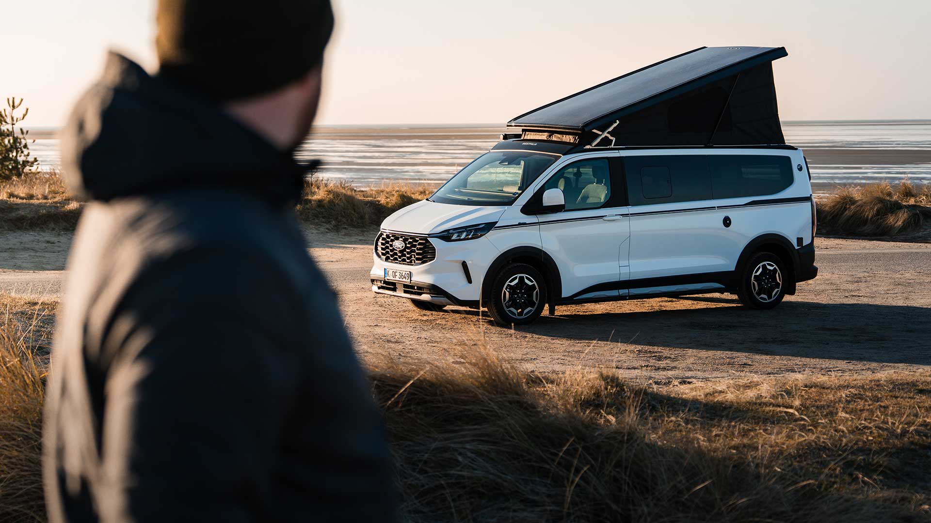 Roter Ford Transit Custom Kleintransporter faehrt durch einen Hafenbereich