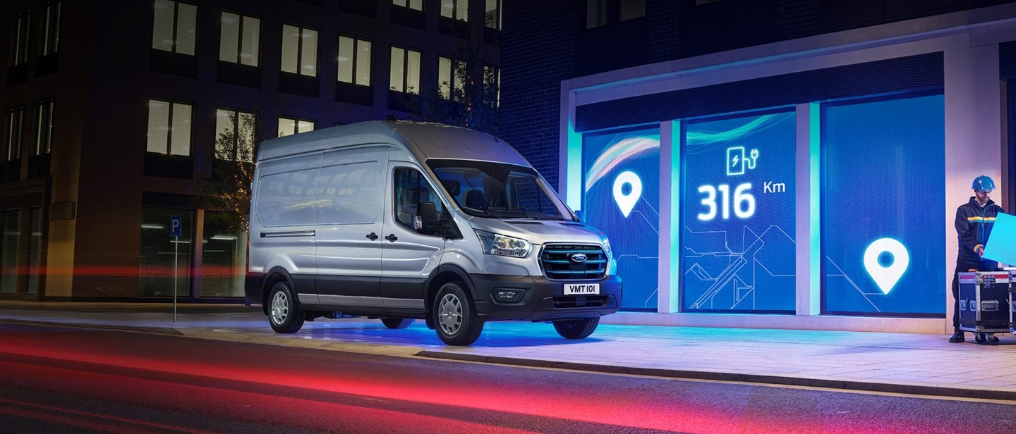 New Ford E-Transit in front of depot in city in night 3/4 front view