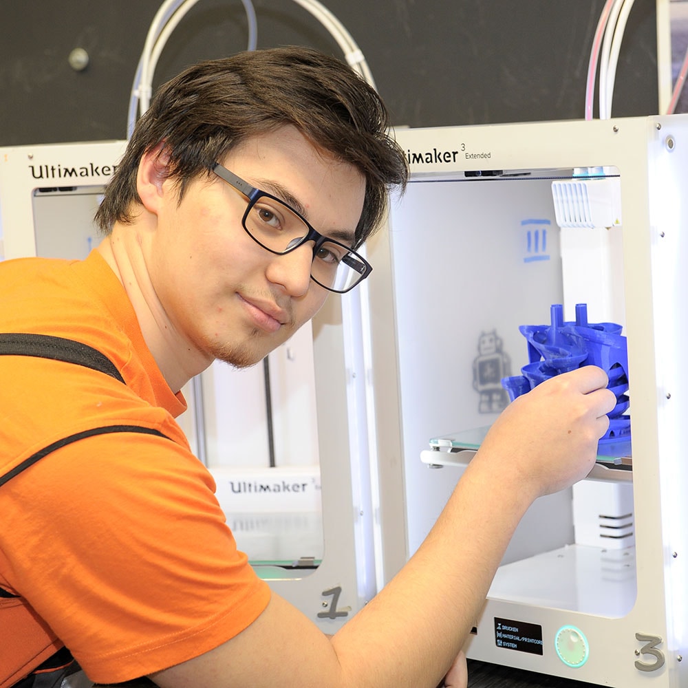 Eine Nahaufnahme einer Person, die ein blaues 3D-Druckmodell aus einem Ultimaker nimmt.