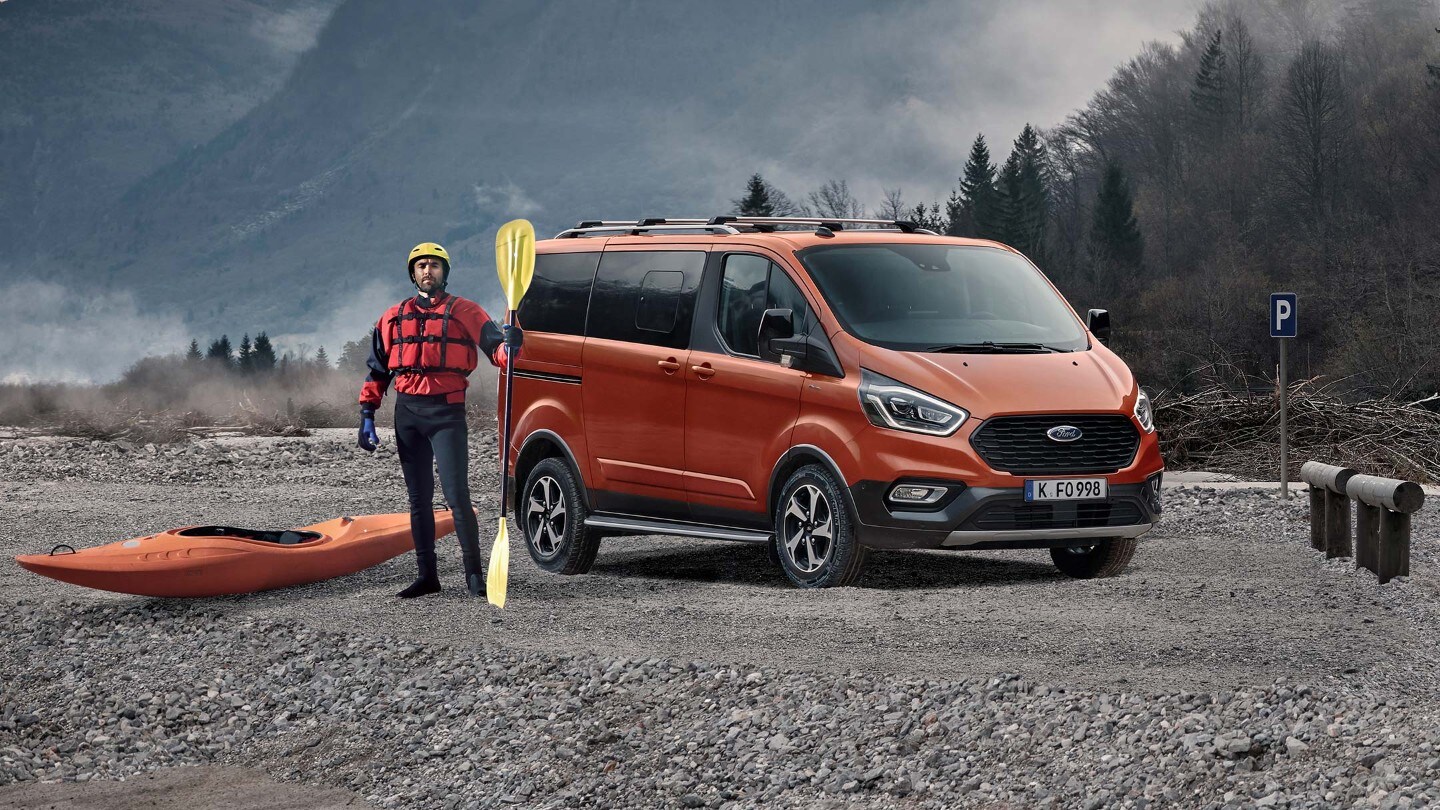 A kayaker standing next to orange Ford Transit Custom