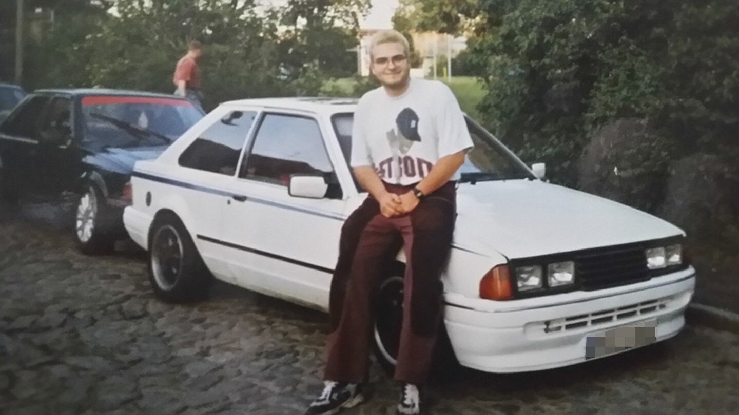 A man sitting on a hood of a white Ford