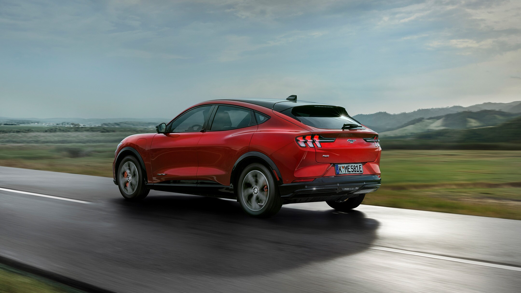 Red Ford Mustang Mach-E driving on a country road