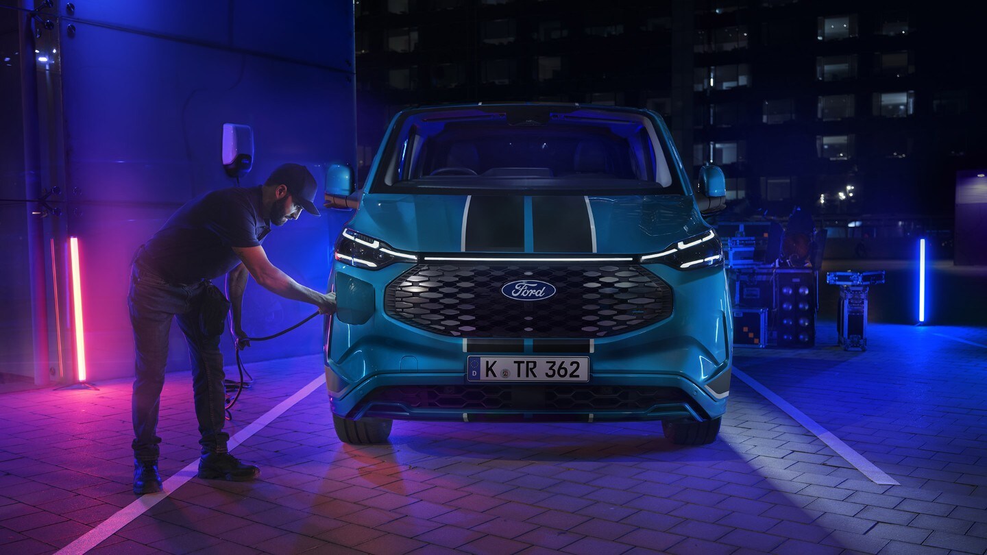 Person plugging in charger to Blue Ford Transit Custom Sport