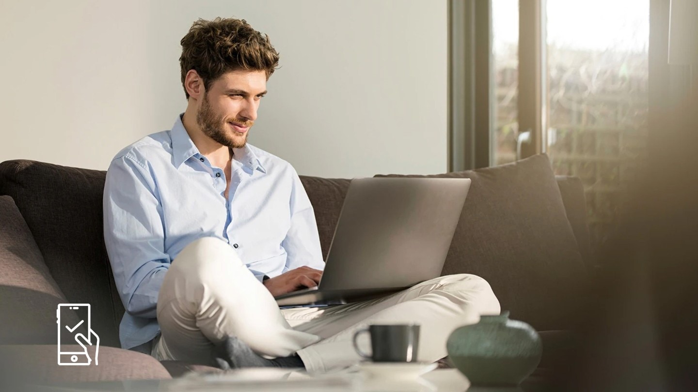 Ein Mann sitzt auf einem Sofa vor einem Laptop