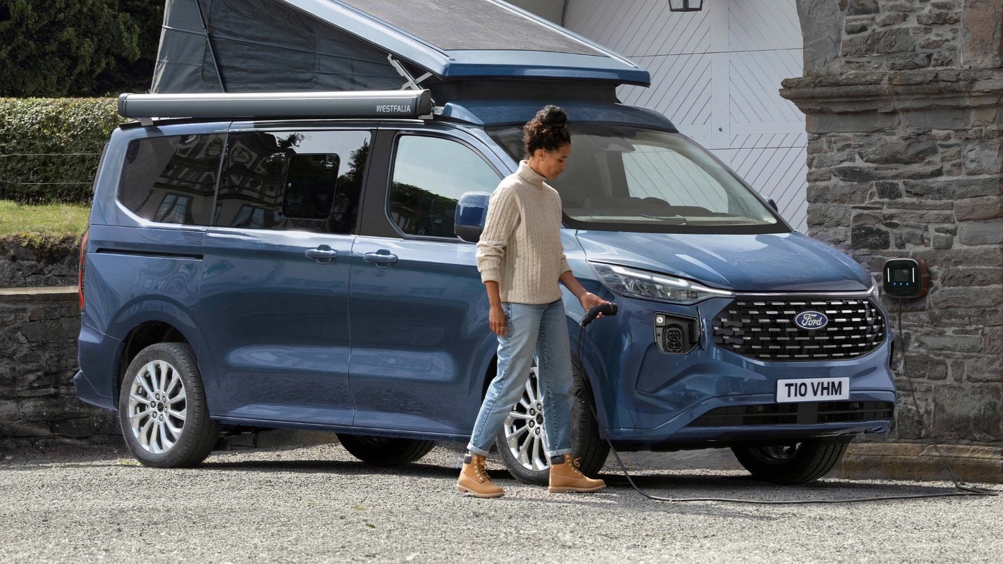 Eine Frau schließt ein Ladegerät an den neuen Ford Nugget Plug-in-Hybrid an. 