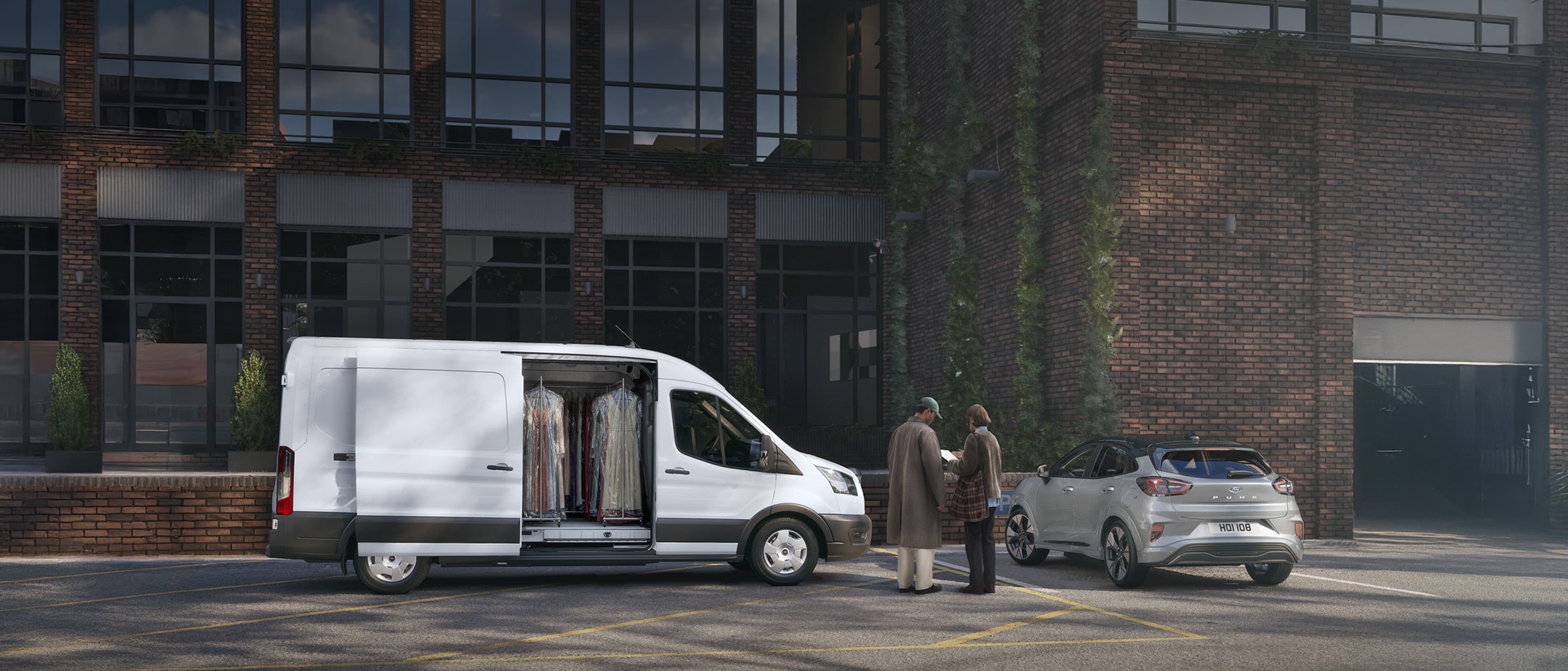 roter Ford Transit Costum wird von zwei Menschen beladen