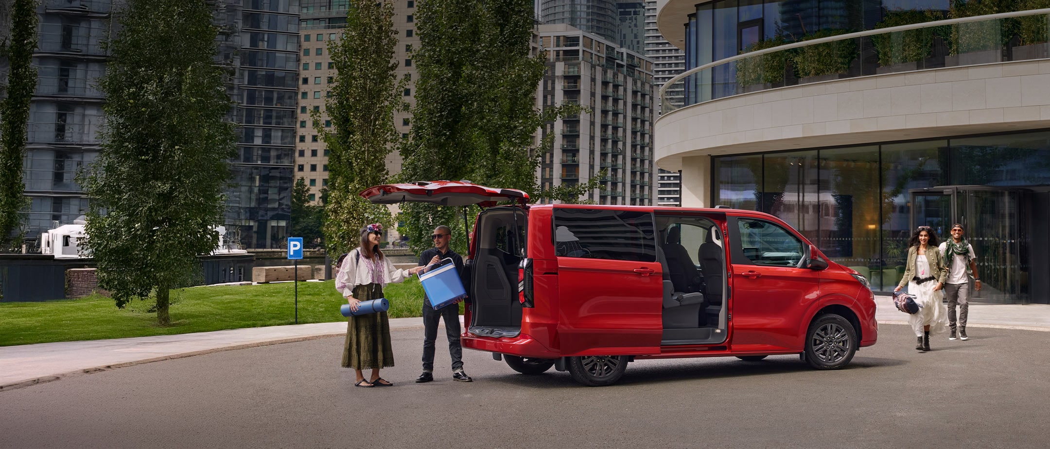 roter Ford Transit Costum wird von zwei Menschen beladen