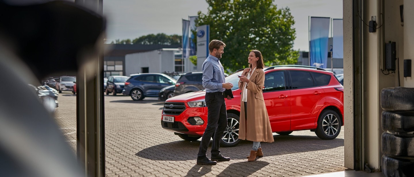 Mann auf dem Fahrersitz eines Ford-Fahrzeugs, auf seinem Handy