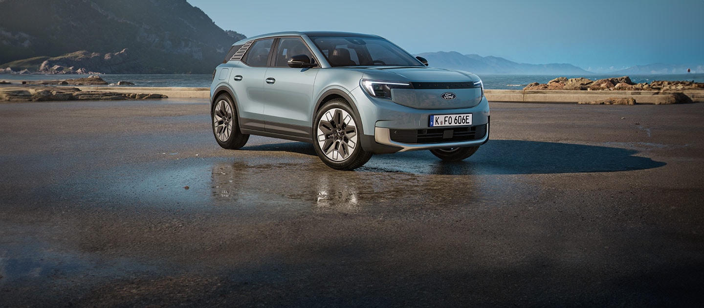 Ein hellblauer Explorer parkt auf einer Straße vor einer Küstenlandschaft.