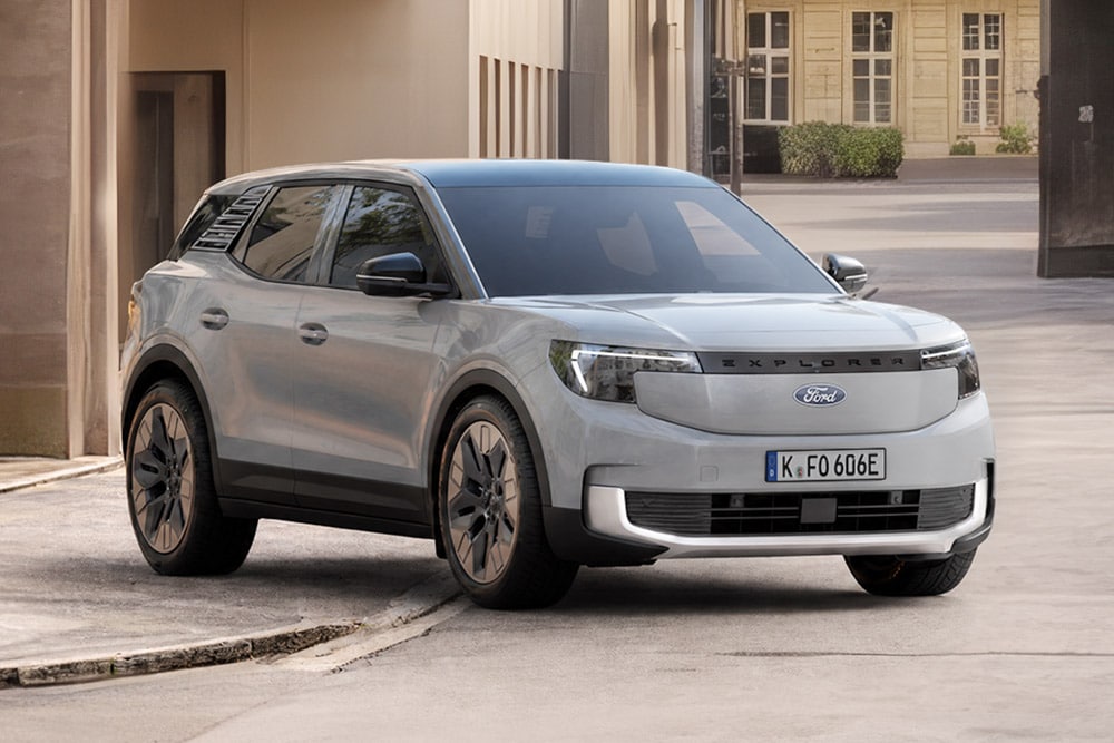  Ein hellgrauer Ford Explorer steht auf einer Straße, von vorne schräg gesehen, vor einem Gebäude.