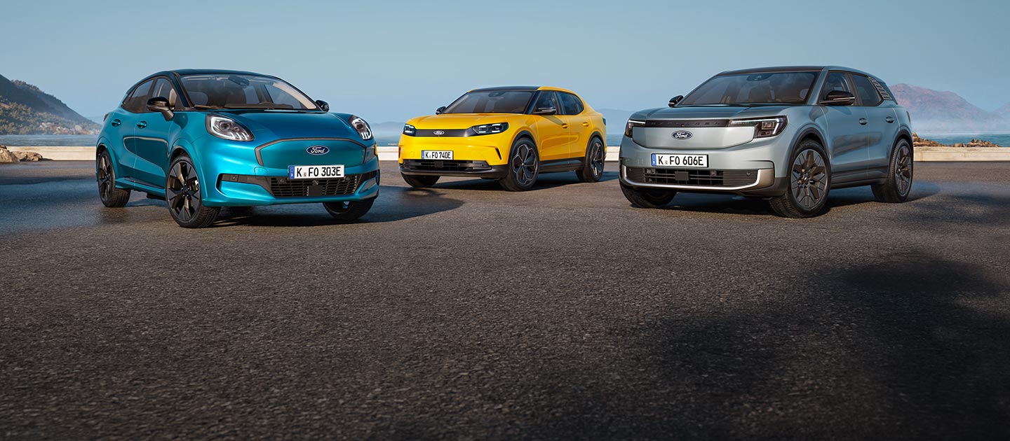 Ein hellblauer Puma Gen-E parkt auf einer Straße vor einer Küstenlandschaft.