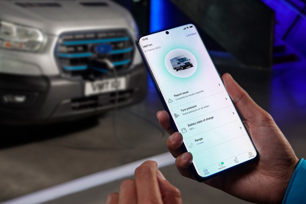 Hand hält ein Telefon mit Informationen über einen Ford E-Transit.