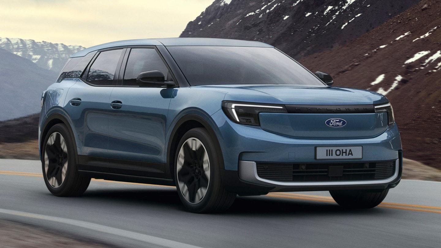 Ein hellblauer Ford Explorer fährt auf einer Asphaltstraße. Im Hintergrund sind Berge zu sehen.