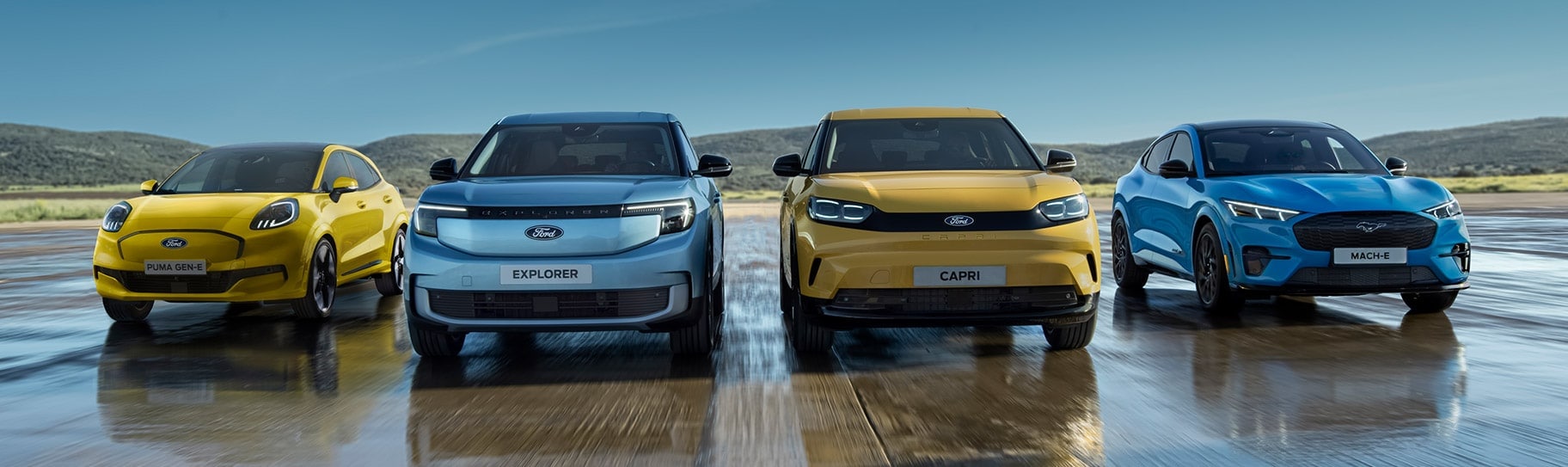 Vier Ford-Modelle nebeneinander: Puma, Explorer, Capri und Mustang Mach-E auf nasser Fläche.
