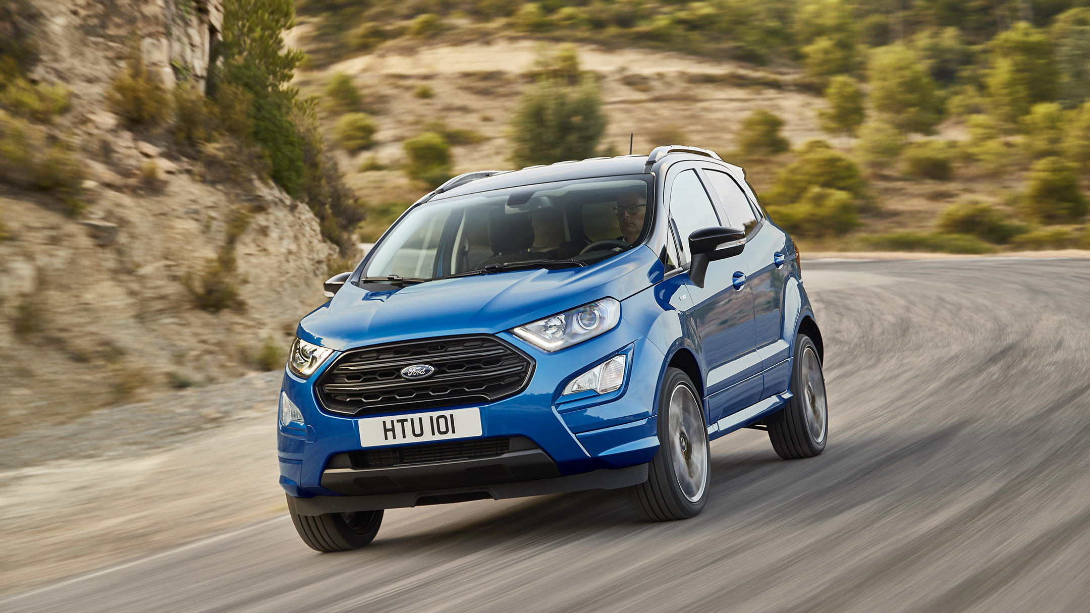 Ford EcoSport in blau. Dreiviertelansicht vorne. Fahrend in einer Gebirgslandschaft