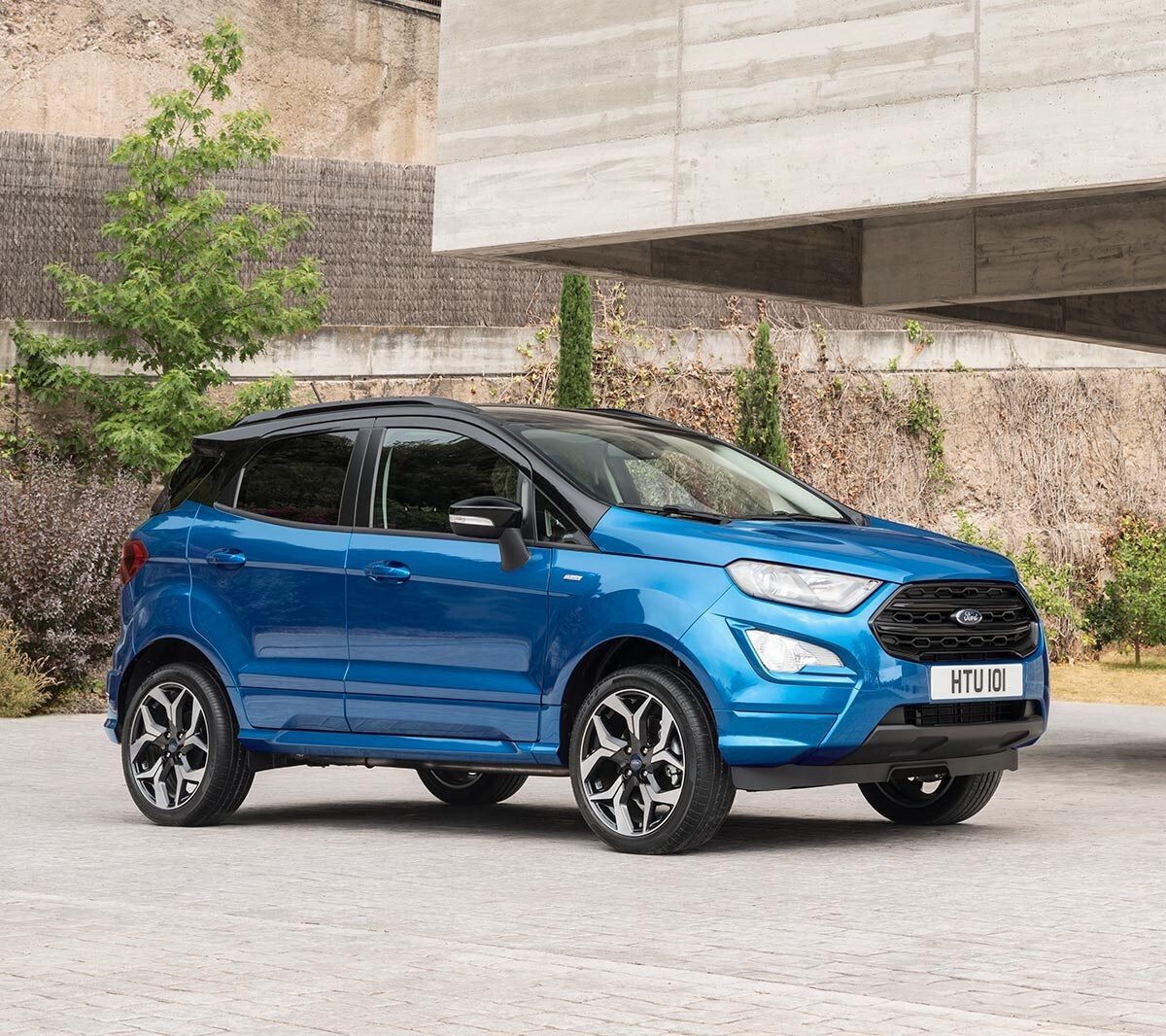 Ford EcoSport in Blau. ¾-Frontansicht. Parkend vor einem modernen Gebäude