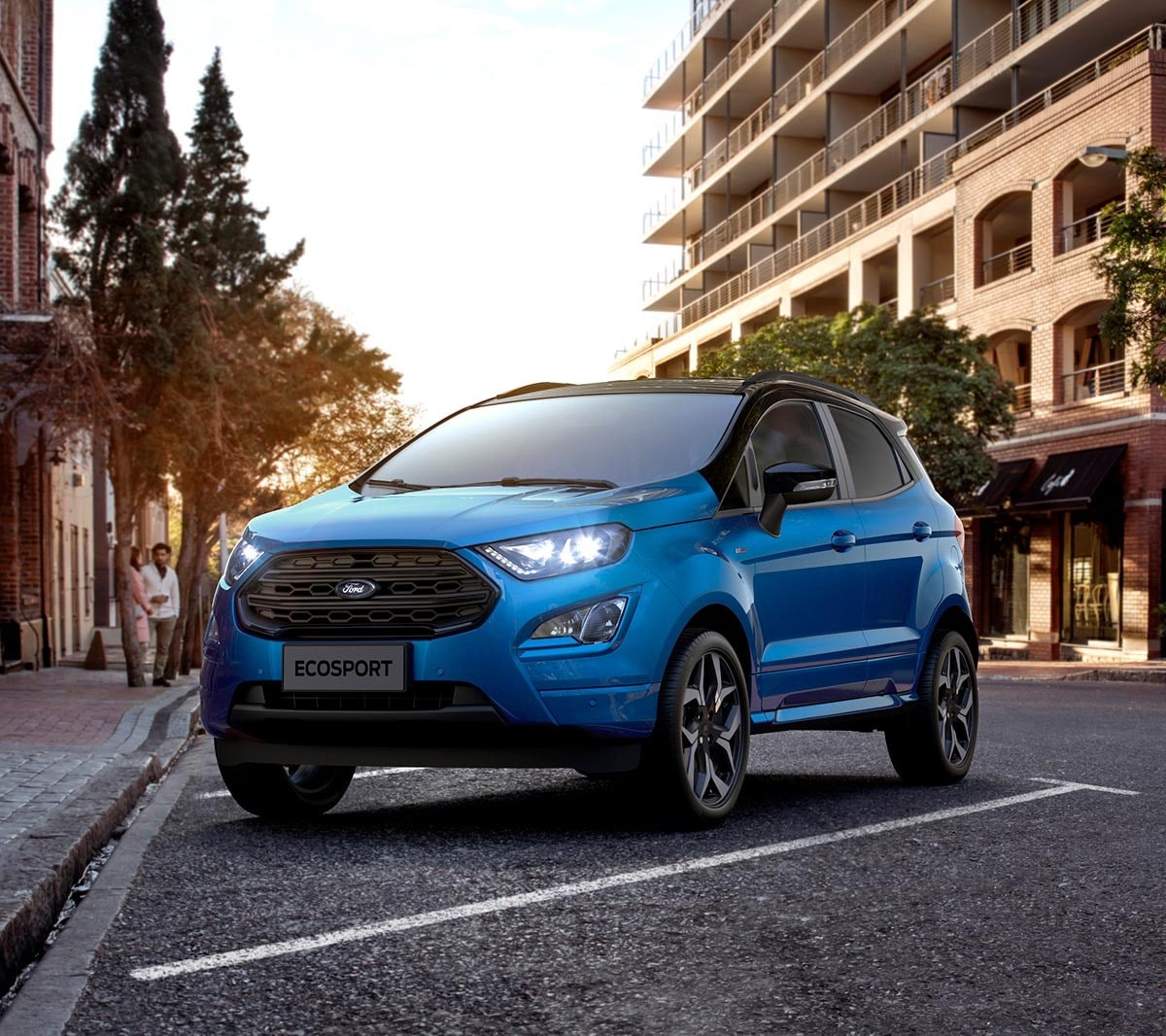 Ford EcoSport in Blau. ¾-Frontansicht. In einer Parktasche vor großem Gebäude stehend