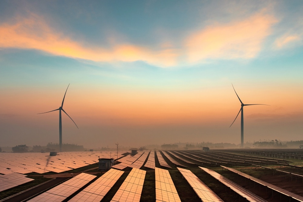 Feld voller Photovoltaik Module mit zwei Windkrafträdern am Horizont