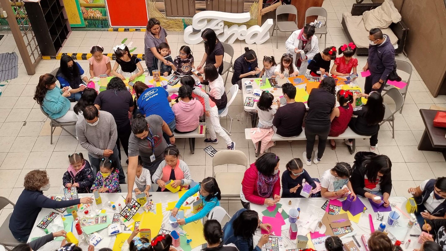 Vogelperspektive auf eine große bastelnde Kindergruppe mit Betreuern