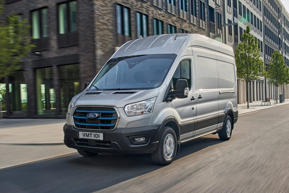 Ford Transit in Grau ¾-Frontansicht fahrend auf Straße in Stadt