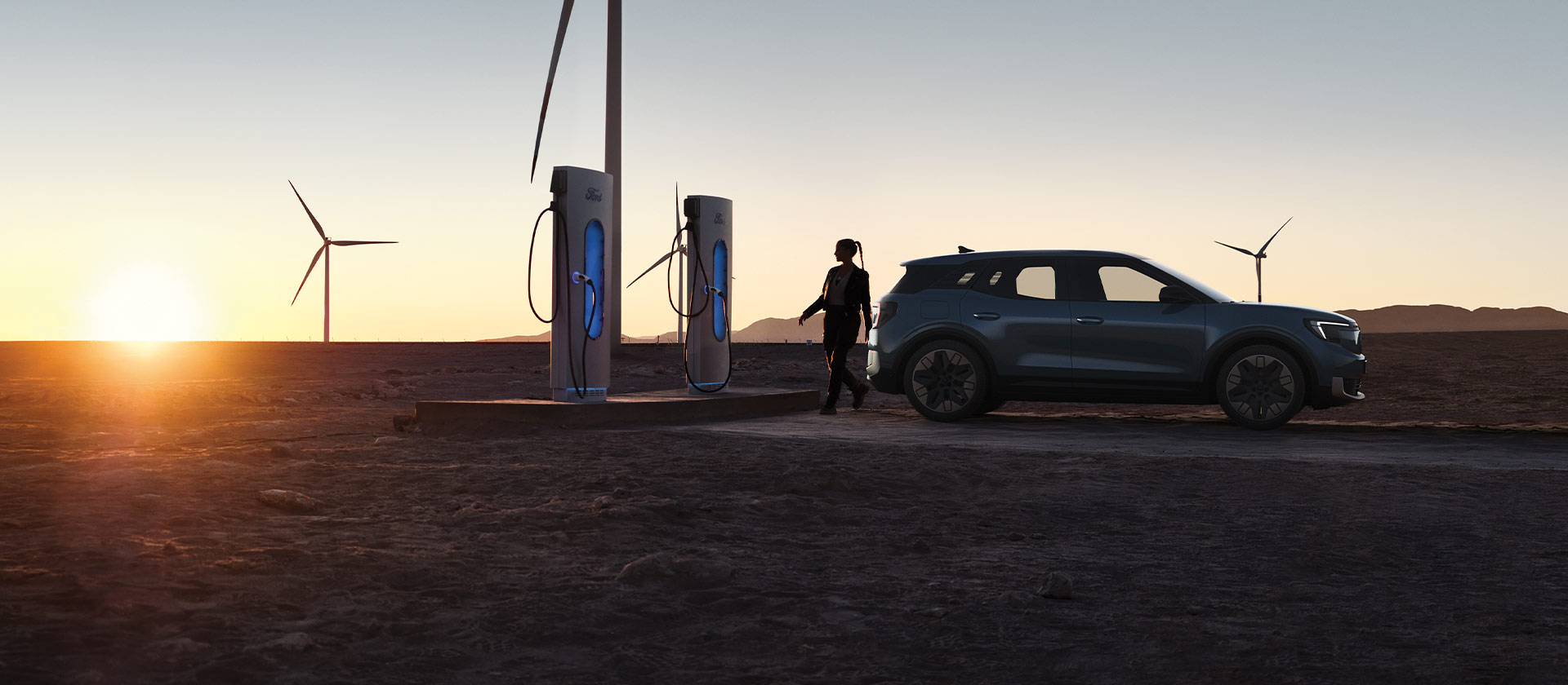 Eine Frau lädt ein Ford Elektrofahrzeug an einer öffentlichen Ladestation auf. 
