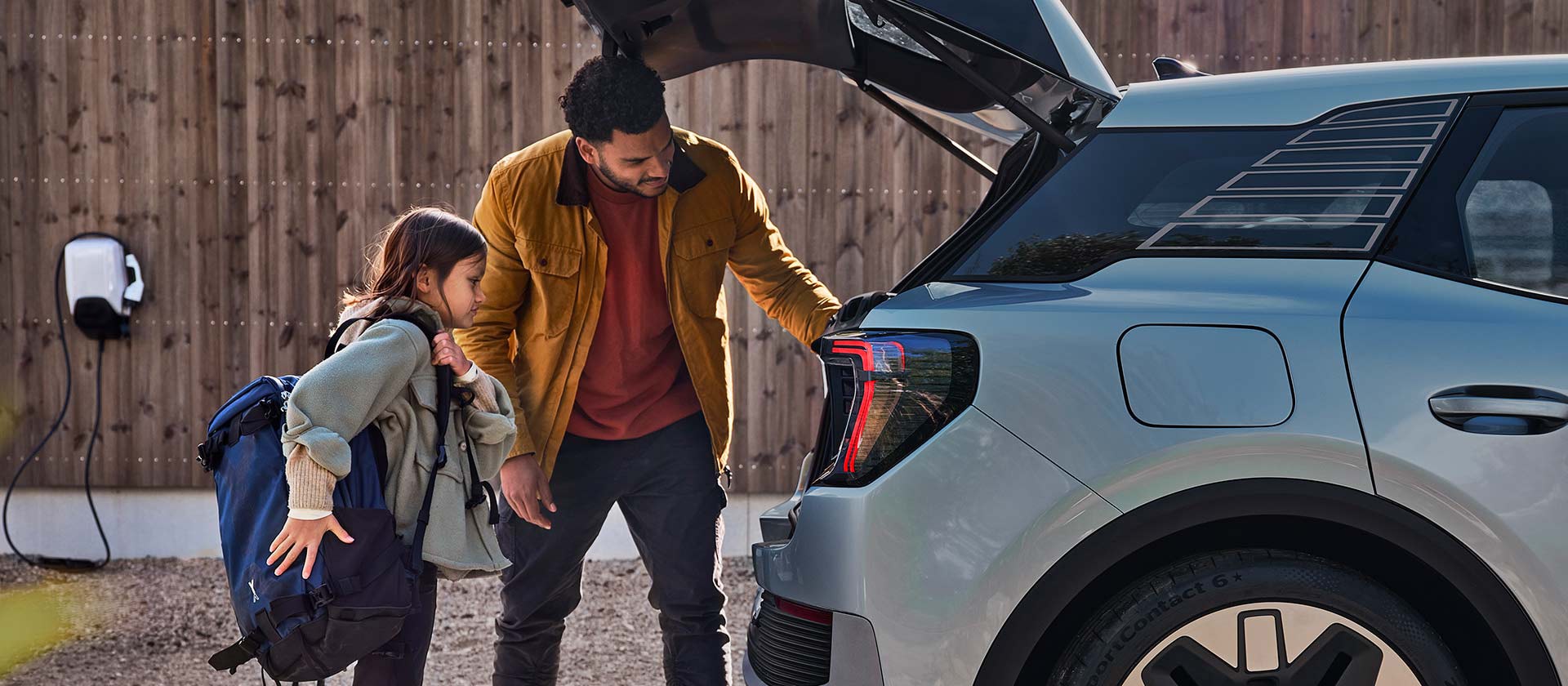 Eine Familie belädt den Kofferraum eines blauen elektrischen Ford Explorer.