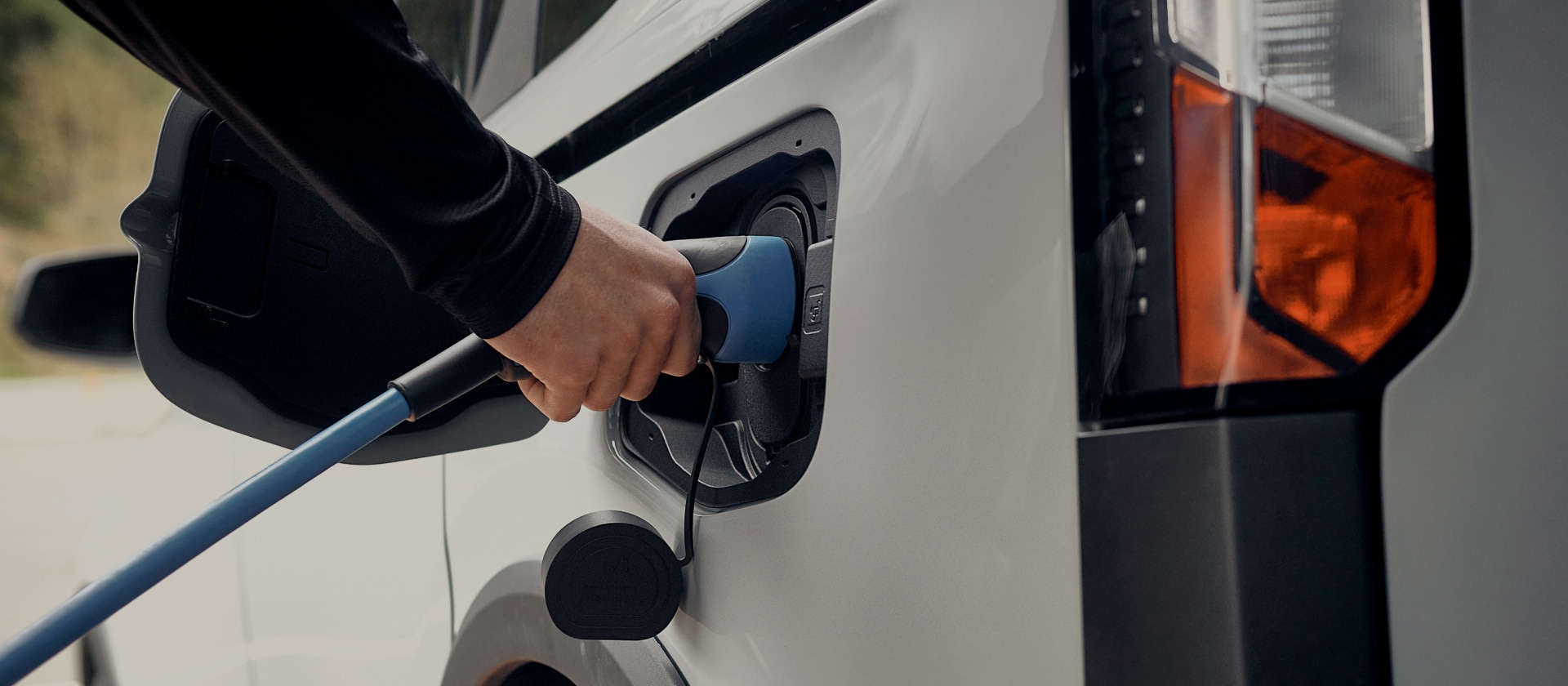 Nahaufnahme eines weißen Ford Elektrofahrzeugs, das an ein EV-Ladestation angeschlossen ist.