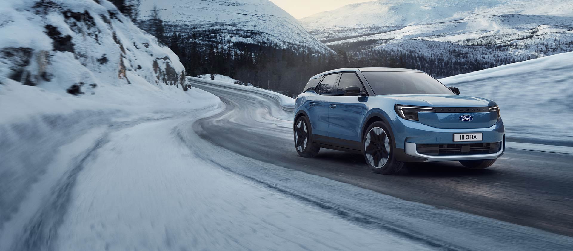 Blauer elektrischer Ford Explorer auf einer verschneiten Bergstraße zur Darstellung der Leistung und Reichweite im Winter.