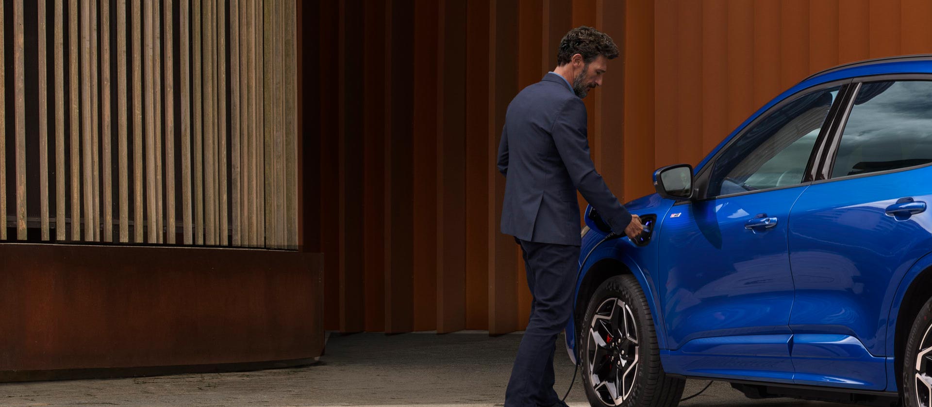 Eine Person schließt ein Ford Plug-in-Hybrid-Fahrzeug an ein Ladegerät an.