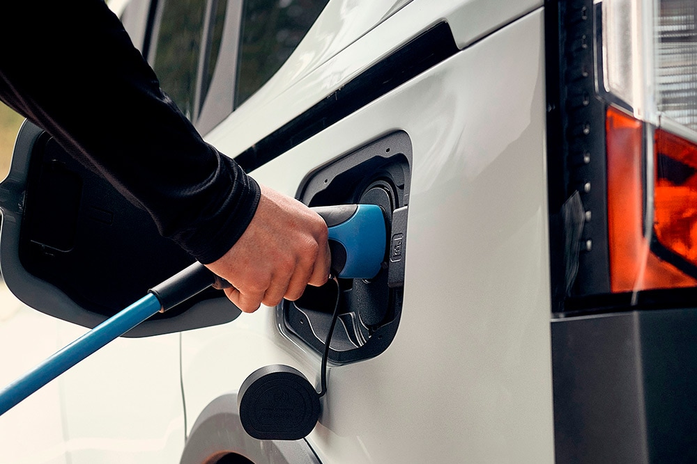 Eine Person schließt ein Ford Elektrofahrzeug an ein EV-Ladekabel an.