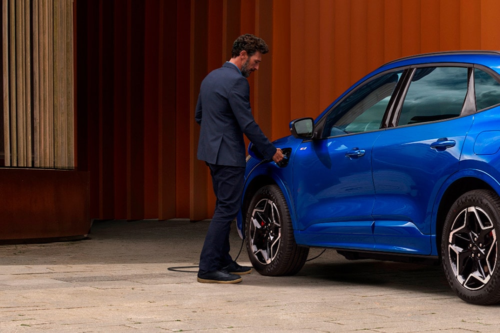 Eine Person schließt ein Ford Plug-in-Hybrid-Fahrzeug an ein Ladegerät an.