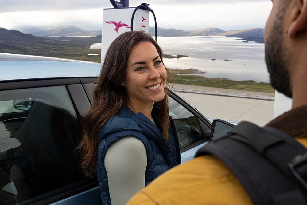 Zwei Personen unterhalten sich, während sie einen elektrischen Ford Explorer an einer IONITY Ladestation laden.
