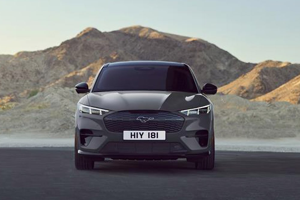 Vorderansicht eines schwarzen Ford Mustang Mach-E, der vor einer bergigen Landschaft geparkt ist.