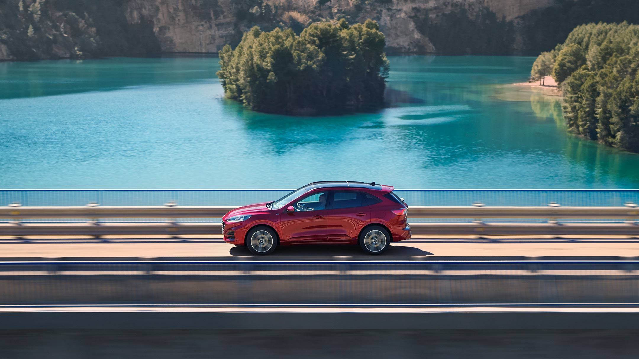 Roter Ford Kuga in Seitenansicht über eine Brücke fahrend