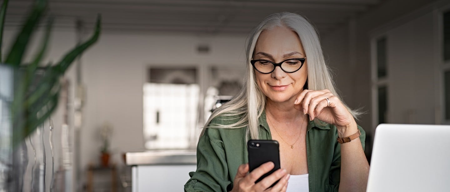 Frau schaut auf Handy mit charging-App neben Mach-E