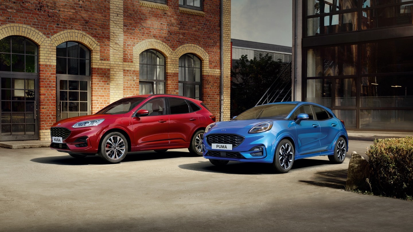 Ford Kuga in Rot und Ford Puma in Blau parkend vor Backsteingebäude