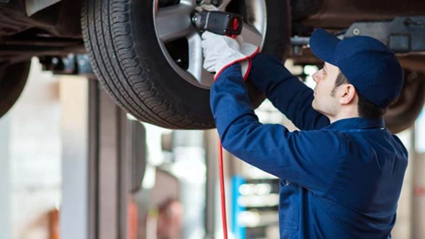 Mann wechselt Reifen an einem Auto auf einer Hebebühne