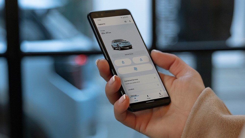 Nahaufnahme einer Hand, die ein Smartphone hält und mit der FordPass-App interagiert.