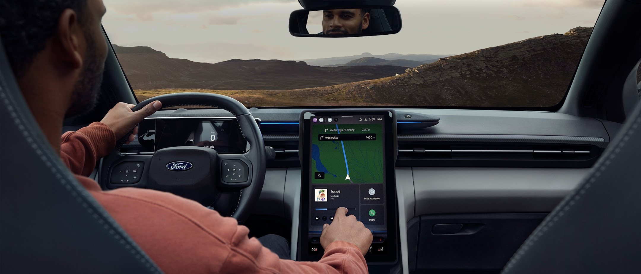 Ein Mann sitzt auf dem Fahrersitz eines vollelektrischen Ford Explorer und bedient den großen SYNC-Touchscreen.