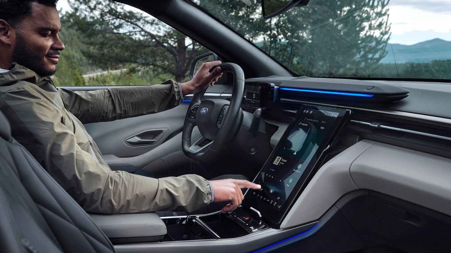 Ein Mann sitzt auf dem Fahrersitz eines Ford Explorer und bedient den großen SYNC Move-Touchscreen.