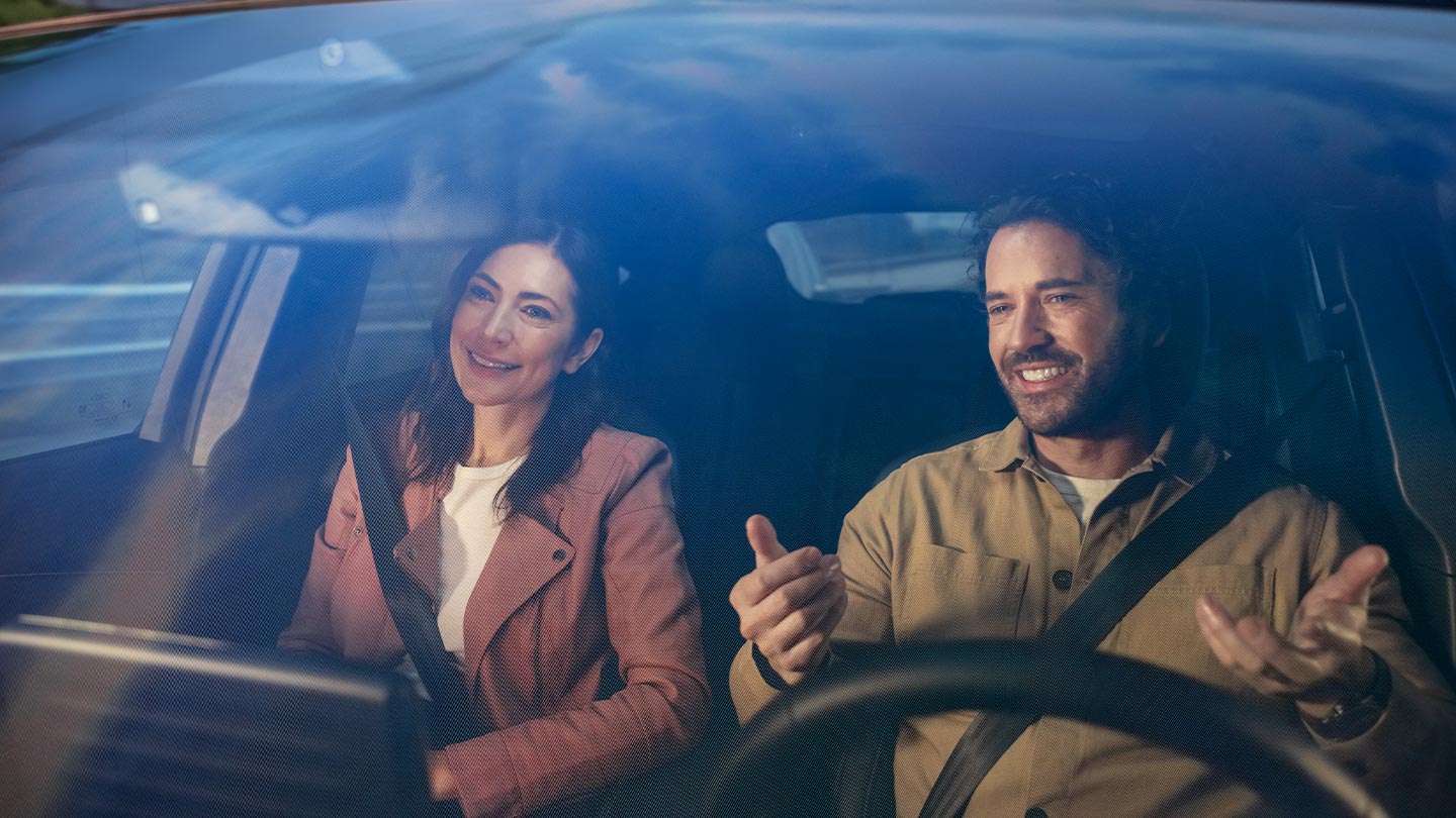 Zwei angeschnallte Personen sitzen in den Vordersitzen eines Ford Fahrzeugs.