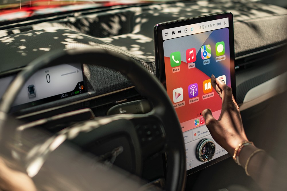 Eine Person bedient den Infotainment-Bildschirm im Innenraum eines Ford Mustang Mach-E.