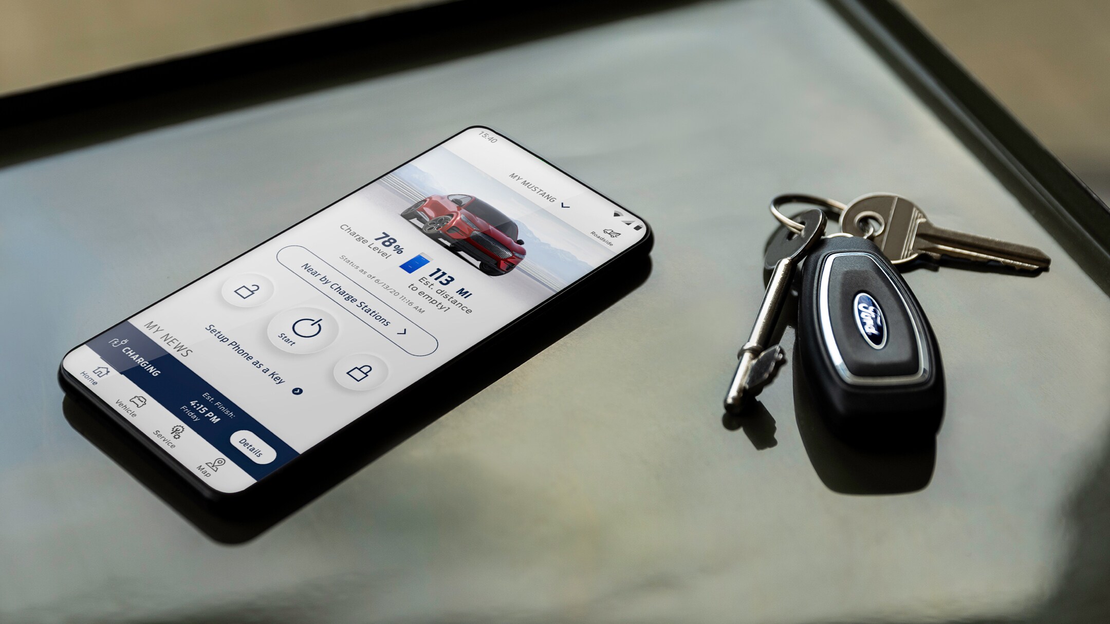 Ein Telefon, auf dessen Bildschirm die FordPass-App angezeigt wird, liegt auf einem Schreibtisch neben einigen Autoschlüsseln.