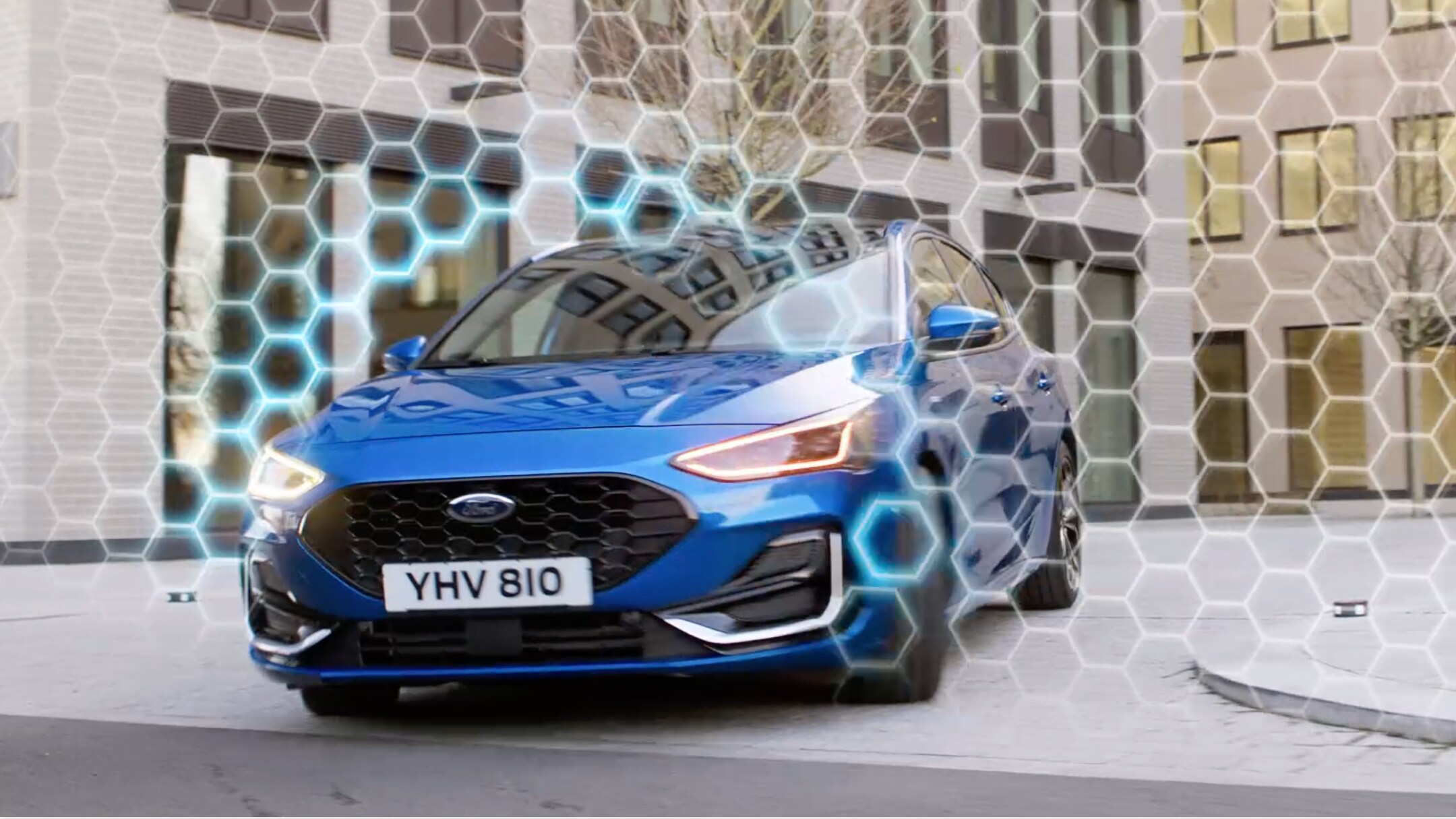 Ford Focus in Blau in der ¾-Frontansicht fährt um die Kurve und durchbricht eine animierte Schutzschildgrafik