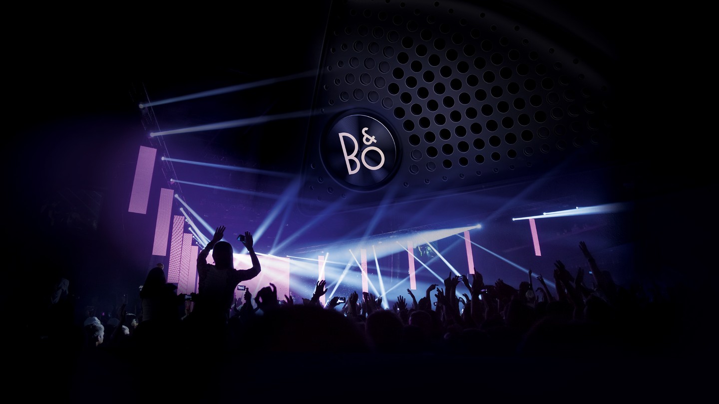 Party und tanzende Menschen in einem Club. Bang & Olufsen Lautsprecher mit Logo im Hintergrund